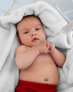 Newborn baby being photographed for a UAE passport at home using soft, indirect lighting